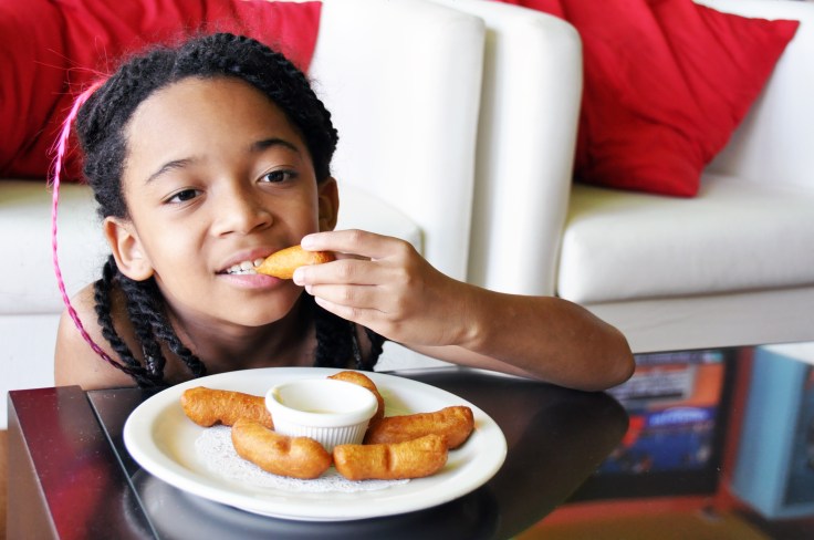 little girl eating a thai donut